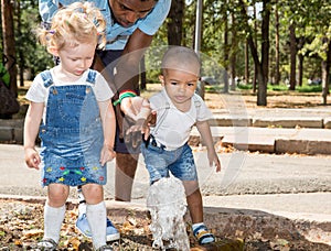 Black man and Group of happy children playing in park.