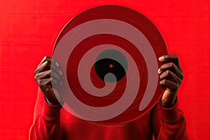 Black man hand holding old vinyl retro record. Vinyl gramophone record on red background.