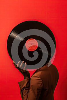 Black man hand holding old vinyl retro record. Vinyl gramophone record on red background.