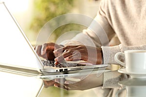 Black man hands typing on a laptop at home