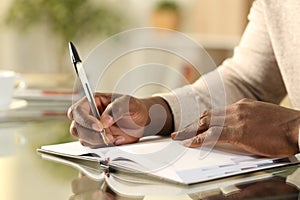 Black man hands writing reminder on agenda