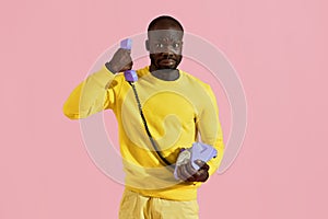 Black man having unpleasant phone call on pink background photo