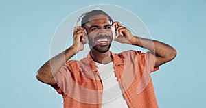 Black man, headphones and dancing to music with happiness and energy in studio on blue background. Techno, rave and fun