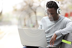 Black man with headphones e-learning using laptop