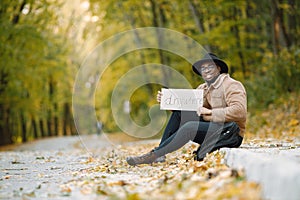 Black man hitchhiking on a road and holding a sign anywhere photo