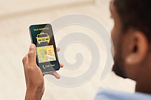 Black man holding cellphone with taxi app interface