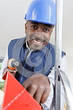 black man holding drill at construction site