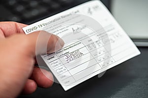 Black man holding a Janssen covid 19 vaccination record in hand