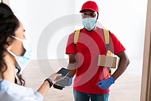 Black man holding POS machine client paying with smart phone