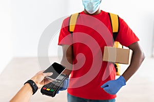 Black man holding POS machine client paying with smart phone