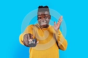 Black man holding remote control in hand and pointing it at camera