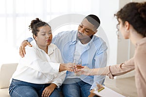 Black man husband comforting crying wife, couple attend family therapy