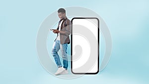 Black man leaning on white empty smartphone screen, using cellphone photo