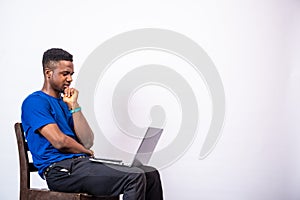 Black man looking puzzled while using his laptop