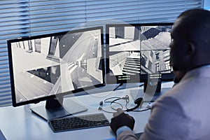 Black man looking at surveillance camera footage in security center