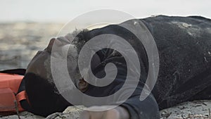 Black man with lunges trauma deeply breathing lying on beach, natural disaster