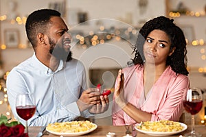 Black man making proposal with ring, woman rejecting