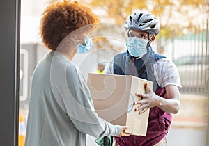 Black man, mask and delivery with box for woman at house for logistics, cargo and safety from covid 19. Young african