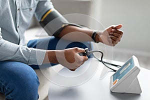 Black Man Measuring Arterial Blood Pressure Having Hypertension Indoors, Cropped