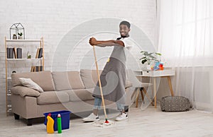 Black man with mop cleaning floor at home