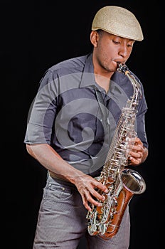 Black man playing the saxophone, feeling the music with white hat