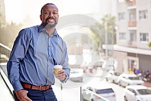 Black man, portrait and office balcony in city with drink, summer and corporate employee for work break. Male