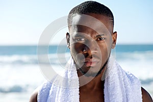 Black man posing with white towel at the beach