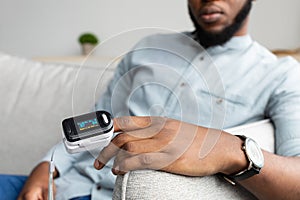 Black Man With Pulse Oximeter Measuring Oxygen Saturation At Home