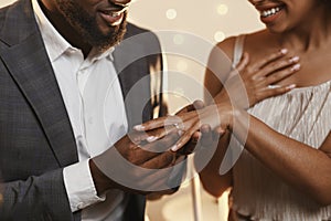Black man putting ring on his woman finger