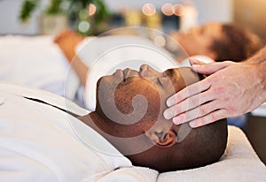 Black man, relax and head massage with therapist hands in a luxury spa, wellness and skincare on a bed. Masseur with