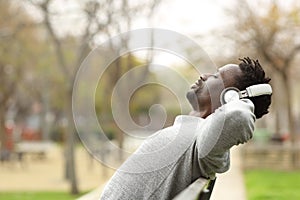 Black man relaxing on a bench listening to music