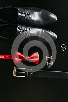 Black man`s shoes, cufflinks, wedding rings, a black belt and a