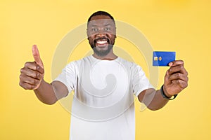 Black Man Showing Credit Card Gesturing Thumbs Up, Yellow Background