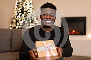 Black Man Showing Gift To Camera Celebrating Winter Holiday Indoor