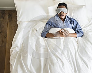 Black man sleeping on bed with eye mask