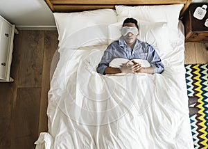 Black man sleeping on bed with eye mask