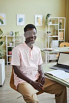 Black man smiling at camera at desk in office