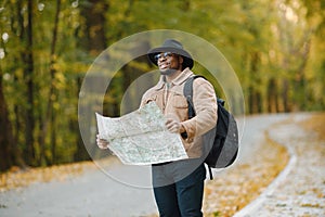 Black man standing on a road and holding a map