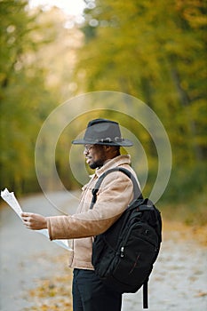 Black man standing on a road and holding a map