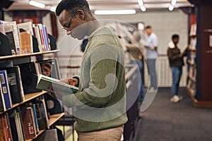 Black man student, reading and library with book, research and education at college to ready for exam. African gen z man