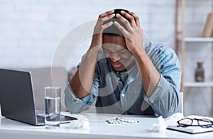 Black Man Suffering From Headache Touching Head Sitting At Workplace