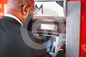 Black man taking money from an ATM