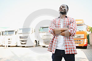Black man truck driver near his truck parked in a parking lot at a truck stop.