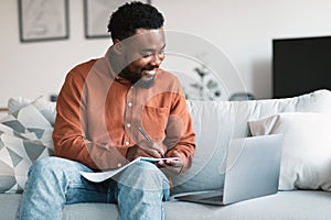 Black Man Using Laptop Taking Notes Learning Online At Home