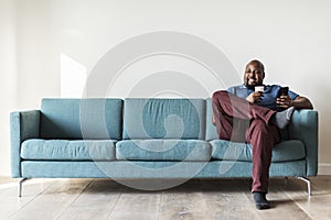 Black man using mobile phone on couch