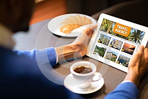 Black Man Using Online Travel Agency Website On Digital Tablet In Cafe