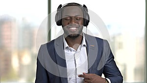 Black man wearing suit and headphone, enjoying music.
