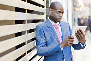 Black man wearing suit looking at his tablet computer