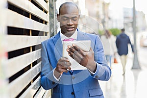 Black man wearing suit and tie looking at his tablet computer