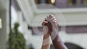 Black man and the white woman raised their hands clenched together into a fist. Black lives matter. Close up. Slow